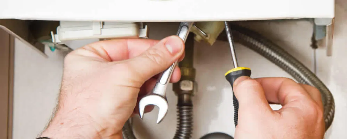Boiler repair technician tightening pipe fittings and connections in Loveland, CO