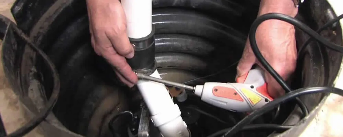 Sump pump installation technician connecting PVC discharge piping in Loveland, CO