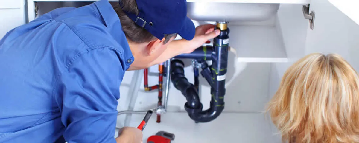 Plumber repairing under-sink drain pipes and fittings in Loveland, CO